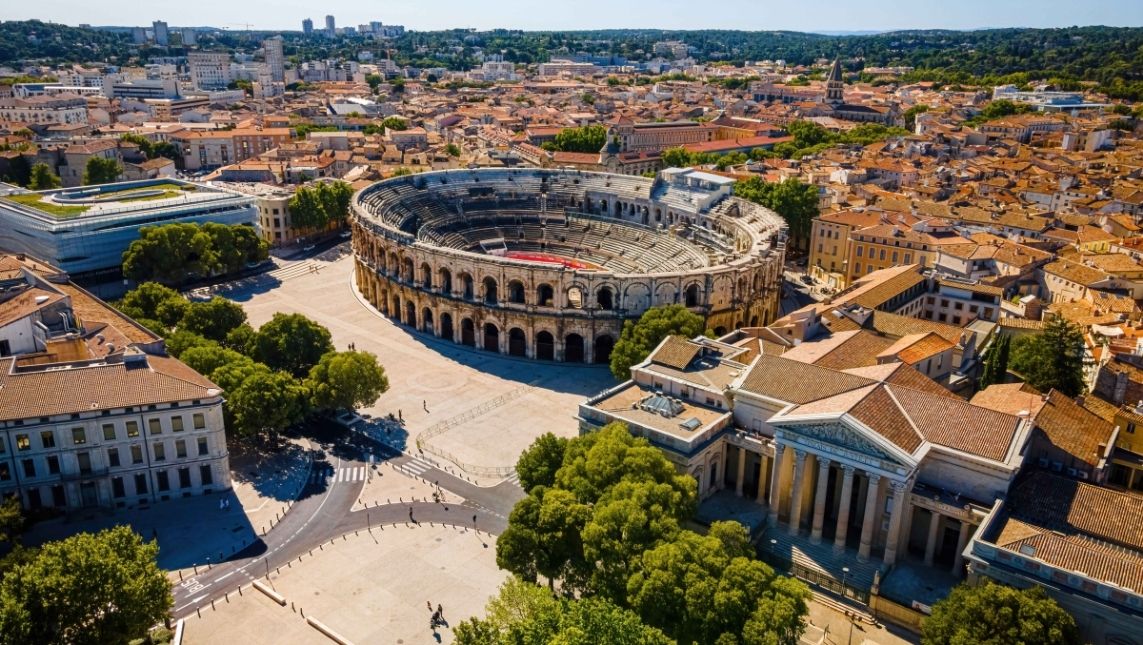 Ville de Nîmes avec l'aperçu depuis le ciel. On voit des monuments en avant et des maisons au loin.