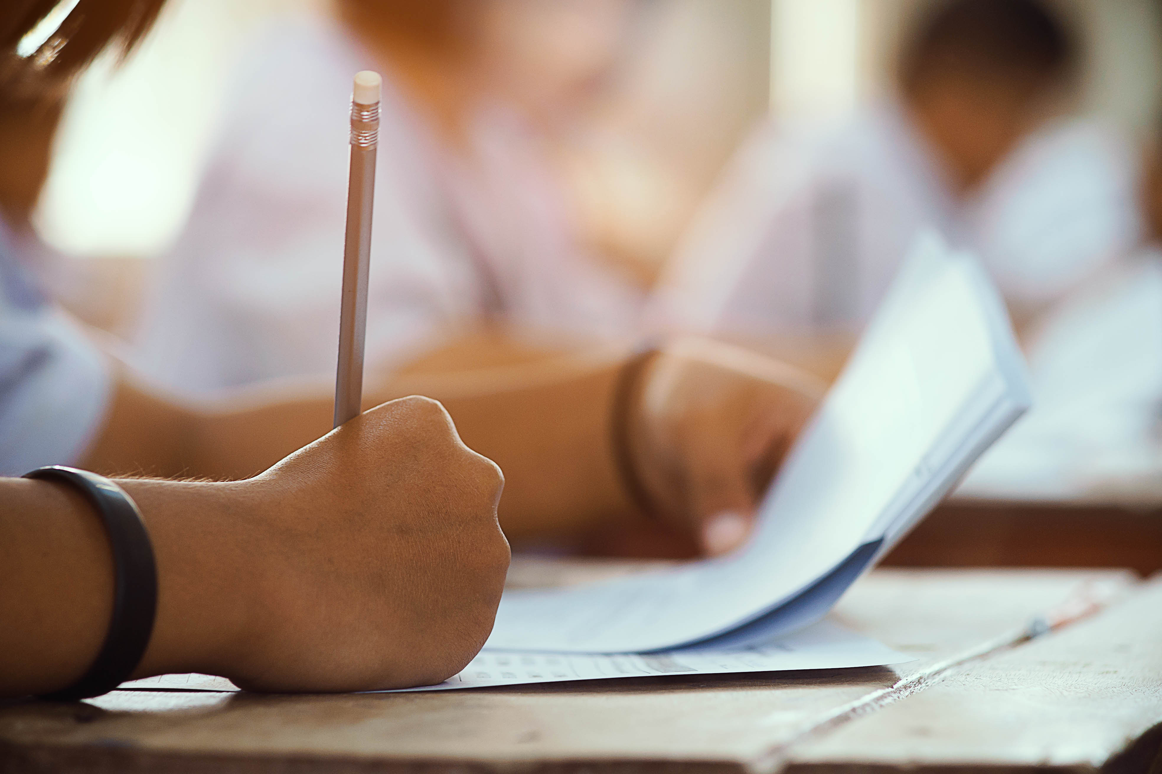 closeup-hand-student-holding-pencil-taking-exam-classroom-with-stress-education-test