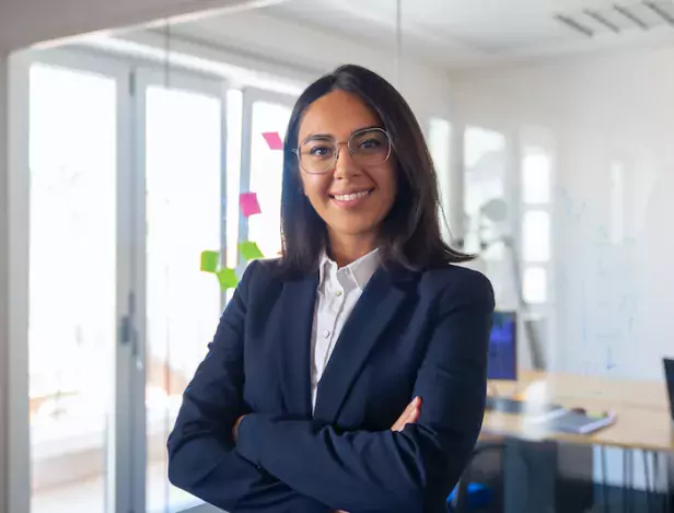 confident-latin-business-leader-portrait-young-businesswoman-in-suit-and-glasses-posing-with-arms-folded-looking-at-camera-and-smiling-female-leadership-concept