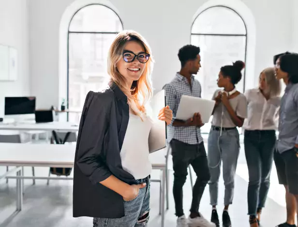 indoor-portrait-of-elegant-business-lady-in-black-jacket-and-her-team-african-office-manager-in-white-sneakers-carrying-laptop-and-talking-with-mulatto-woman-in-jeans
