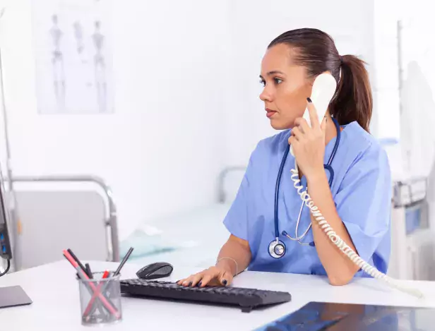 infirmiere-medicale-parlant-patient-au-telephone-au-sujet-du-diagnostic-medecin-soins-sante-assis-au-bureau-aide-ordinateur-dans-clinique-moderne-regardant-moniteur