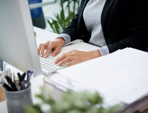 unrecognizable-woman-sitting-desk-office-typing-keyboard